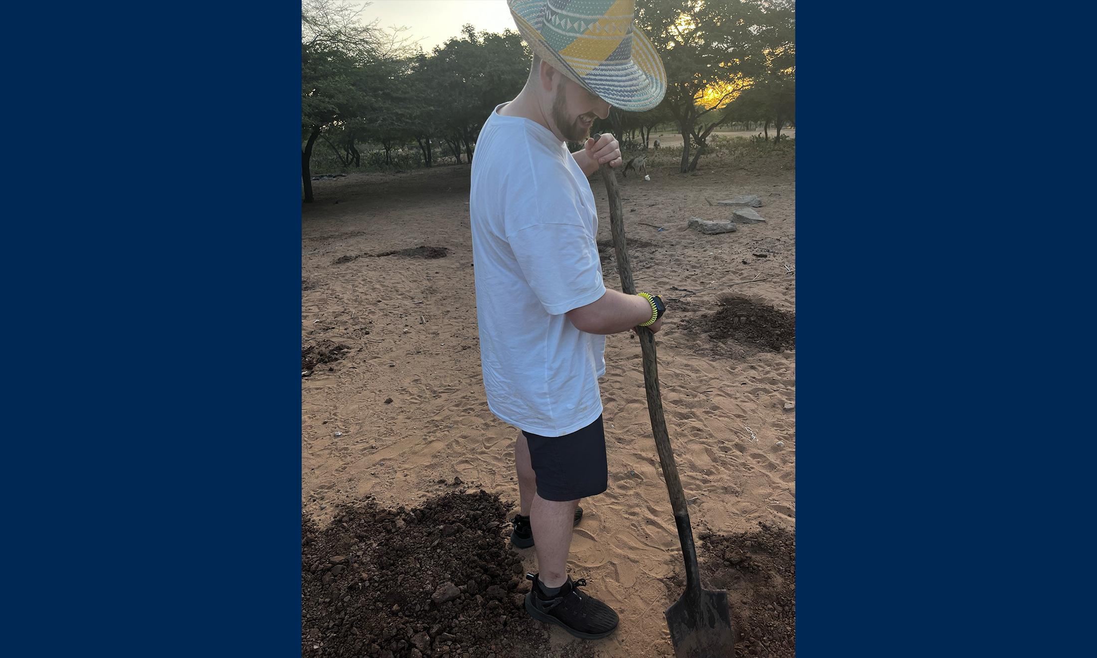 An image of Quinn Simpson digging a post hole